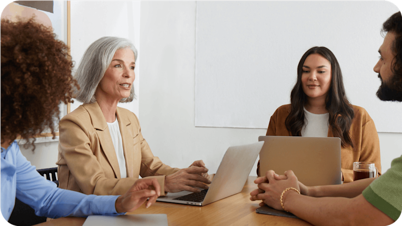 Image of four people sitting at a table talking to each other. The visual suggests the importance of building your B2B marketing automation strategy.