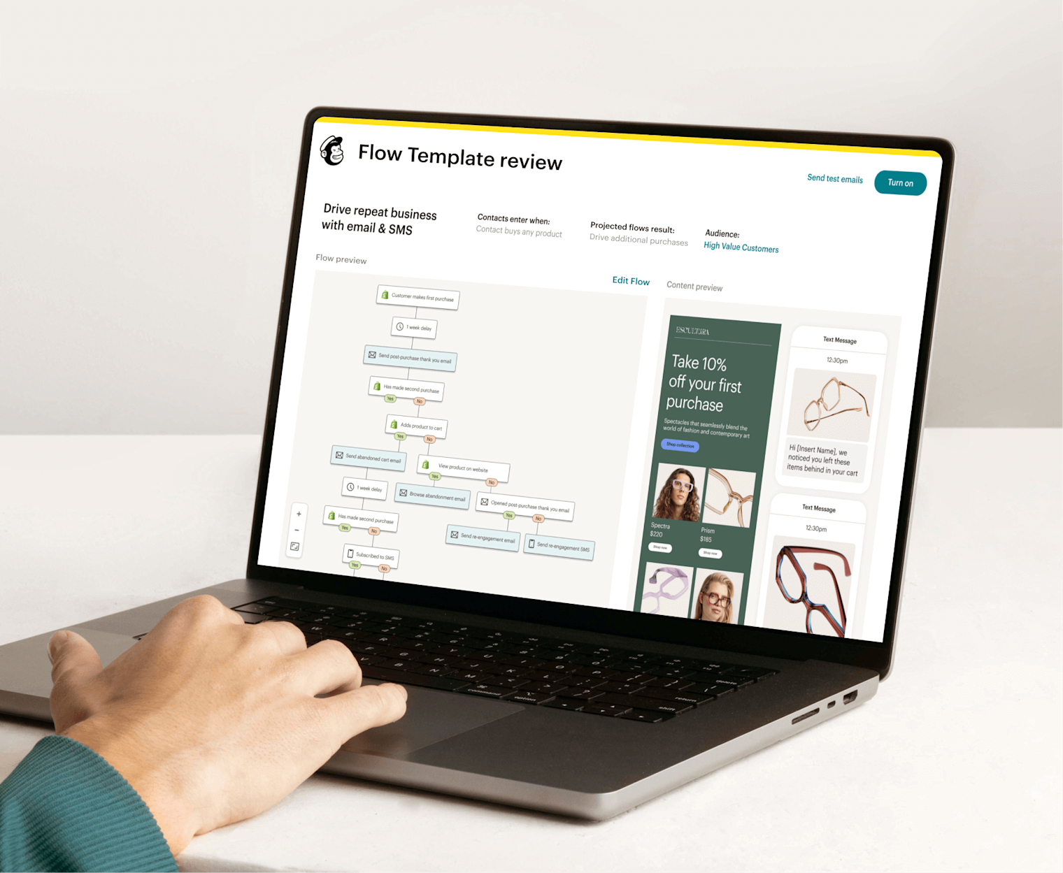 Image of a person sitting at a desk, looking at a laptop screen displaying Mailchimp’s Automation Flow Template review feature. The feature shows a preview of an automation journey and an abstract view of email and SMS interfaces from the fictitious brand Escultura.