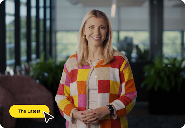 Image of a person standing and smiling with floating Abstract User Interface of a mouse cursor and button. The visual demonstrates how users can explore Mailchimp’s advanced new features.