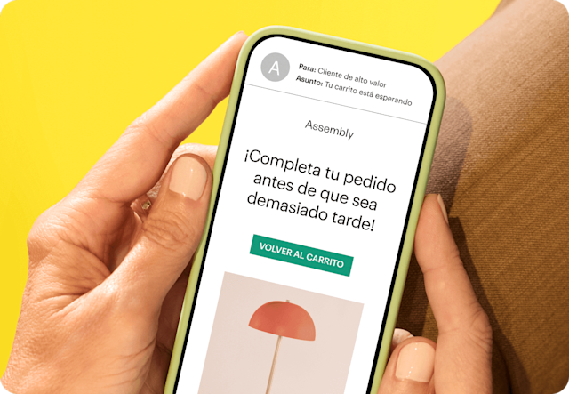 Imagen que representa a una persona sosteniendo un teléfono inteligente que muestra un correo electrónico de la marca ficticia Assembly. La imagen demuestra cómo los negocios pueden usar los activadores del Recorrido del Cliente de Mailchimp para mantenerse al tanto del comportamiento de sus clientes e interactuar con ellos en cuanto muestren interés.
